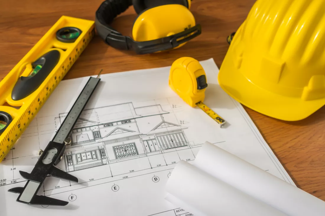 construction-plans-with-yellow-helmet-drawing-tools-bluep