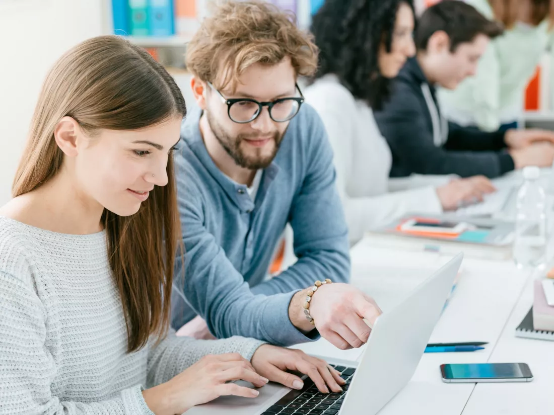 Studenci pracuja razem przy laptopach na zajeciach